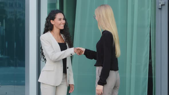 Friendly Smiling Millennial Diverse Female Colleagues Greeting Each Other By Handshaking alt