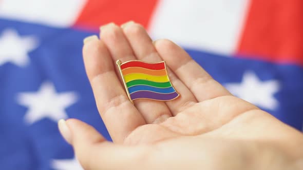 Young woman holding LGBT icon in her hand. American flag on the background. alt