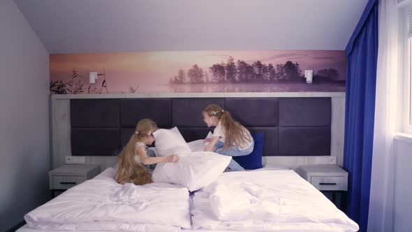 Twins Fighting with Pillows on Bed