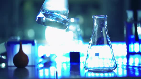 Scientist in Laboratory Doing Chemical Experiment with Liquid in Tube and Flasks alt