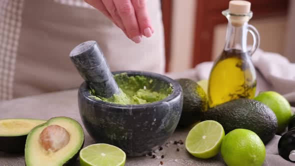 Making Guacamole Sauce Woman Salting Mashed Avocado in a Marble Mortar with Pestle at Domestic alt