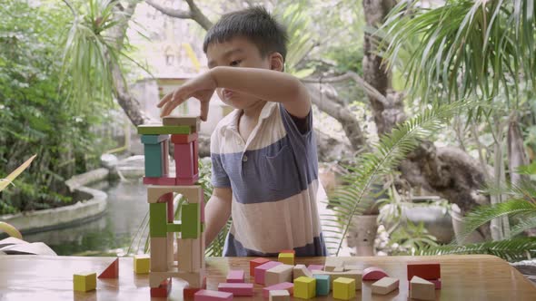 Asian boy playing wooden block toy on table for creative and development with enjoy. alt