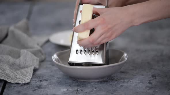 Female Hands Grate Cheese on Kitchen