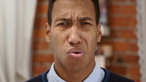 Astonished Young African Man Looking at Camera with Surprise alt