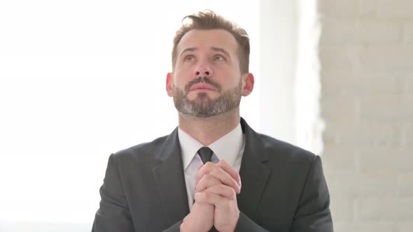 Middle Aged Businessman Praying with Fingers Crossed alt