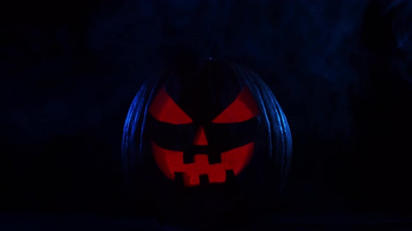 Scary laughing pumpkin and an old skull over the frightening gothic background. alt