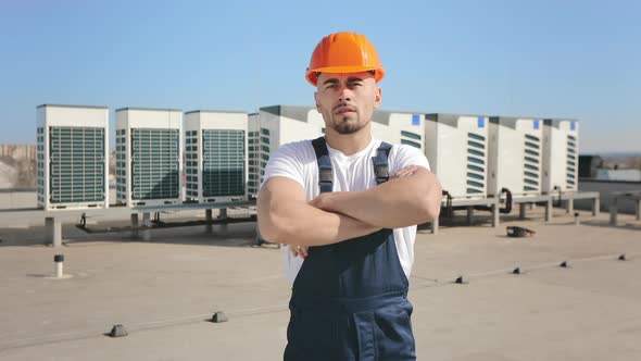 Portrait of a Young Serious Engineer Who is Looking at the Camera and Crossing His Arms alt