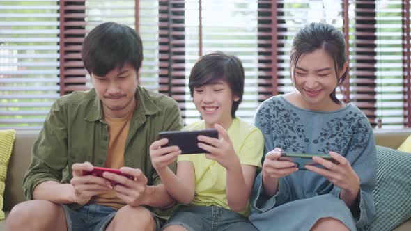 family quality time,asian parent and son sit relax playing game console smartphone at home