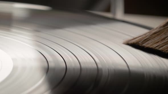 Hand removing dust from a vinyl record with antistatic brush. alt