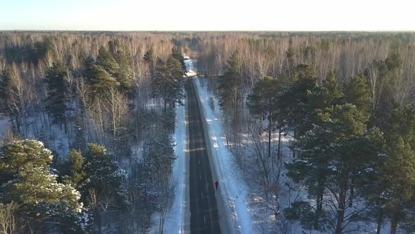 Upper View Athlete Runs Along Snowy Road Among Old Wood alt
