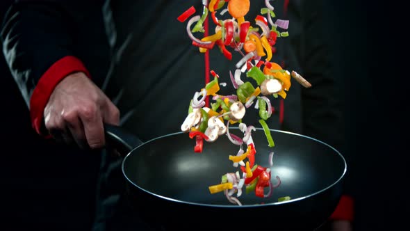 Super Slow Motion Shot of Chef Holding Frying Pan and Falling Vegetables at 1000Fps. alt