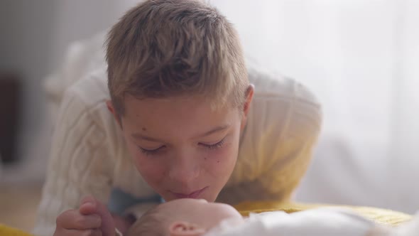 Closeup Portrait Loving Caucasian Teenage Brother Admiring Kissing Infant Baby Sister alt
