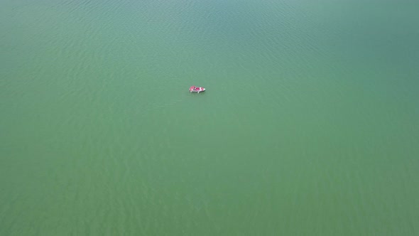 Aerial Approach shot of lake with boat floating in the middle, top down shot alt