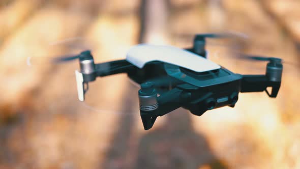 Drone with a Camera Hovers in the Air. Flies Above the Ground in the Forest. Slow Motion alt