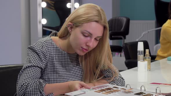 Young Woman Choosing New Hairstyle From Catalogue at Hairdresser Salon alt