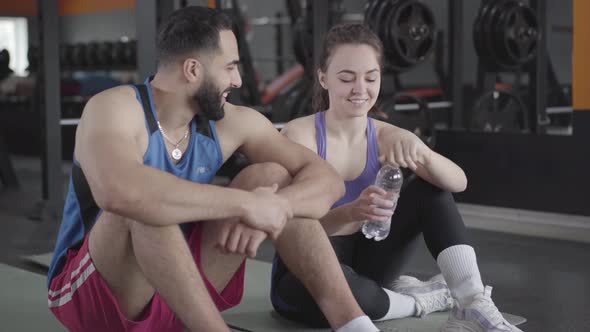 Young Middle Eastern Man Flirting with Slim Caucasian Woman in Gym alt