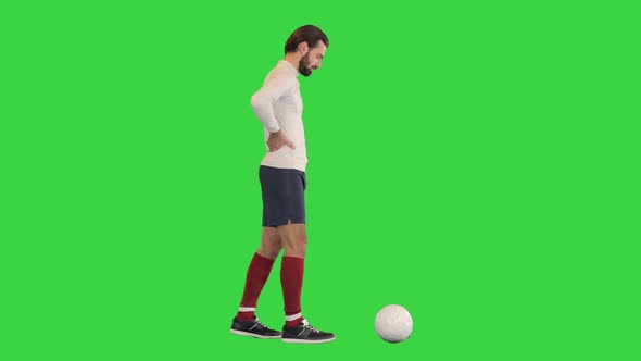 Football Player Walking Slowly and Kicking the Ball on a Green Screen Chroma Key alt