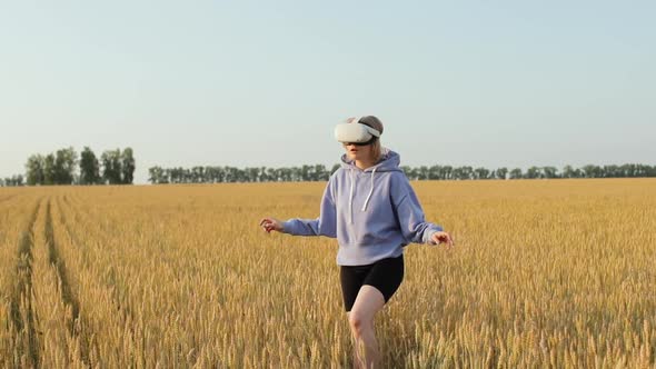 A Beautiful Girl Uses Virtual Reality Glasses in a Wheat Field