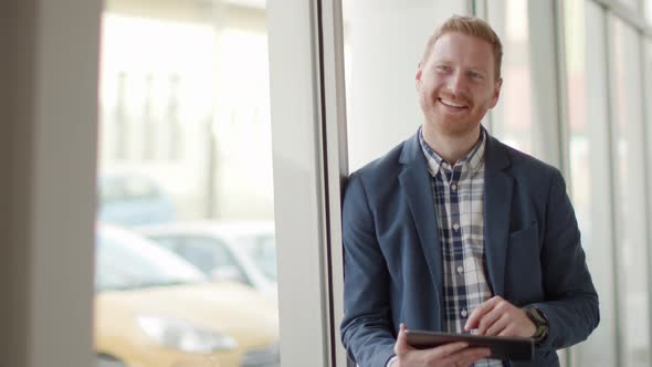 Young handsome businessman standing with digital tablet in the office