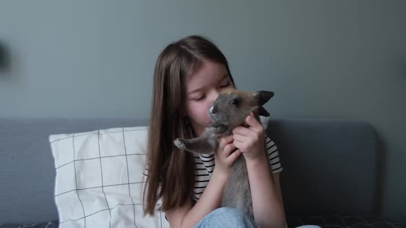 a Little Girl Holds a Rabbit in Her Arms Plays with Him Kisses Him