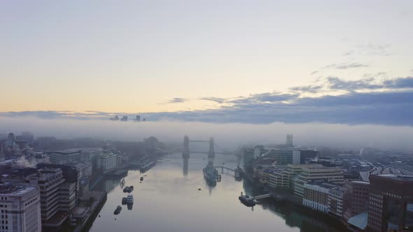Fog over Tower Bridge London thames river at sunrise canary wharf in background alt