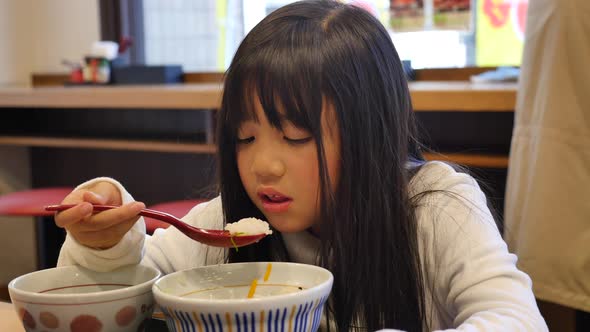 Cute Asian Girl Eating Salmon Roe Rice Bowl  In A Japanese Restaurant  alt