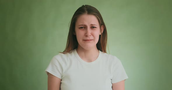 Stressed Woman Cries with Offence Posing for Camera on Green alt