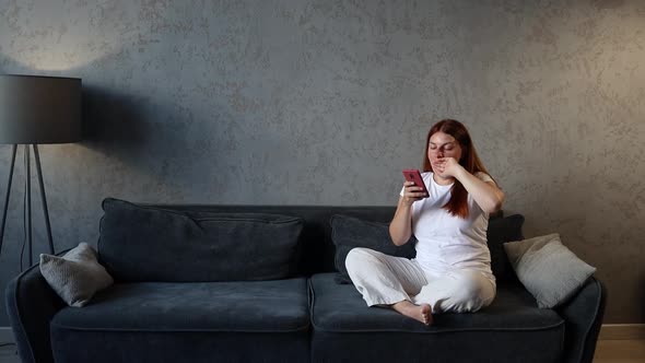 Young Woman Using Digital Phone Watching Social Media at Home Living Room