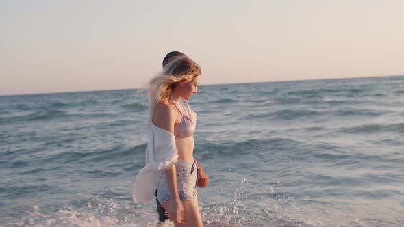 Couple of Young Lovers Holding Hands Walking Along the Beach By the Sea