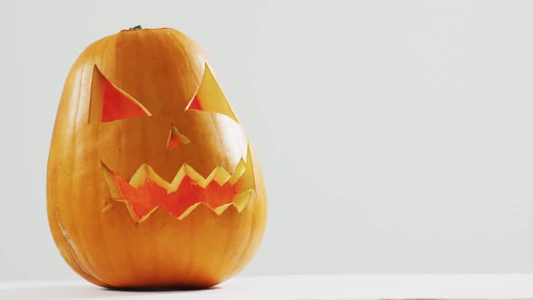 Close up view of scary face carved halloween pumpkin against grey background alt
