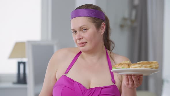 Portrait of Young Plussize Woman Choosing Unhealthy Burgers Holding Plates with Sandwiches and alt