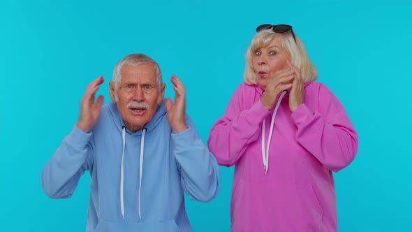 Excited Amazed Grandfather Grandmother Pensioners Raising Hands in Surprise Win Shocked By Victory alt