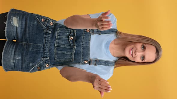 VERTICAL VIDEO POV Smiling Woman Come Here Gesture Waving Hands Posing Isolated on Orange Studio alt