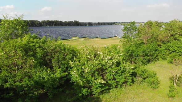 Aerial View of Solar Power Station. Panels Stand in a Row on Green Field. Summer alt