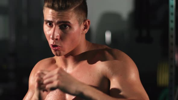 Attractive boxing man training punching at gym