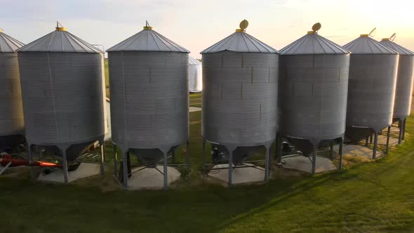 4k drone orbiting around several big grain bins standing in a half circle on small family operated f alt