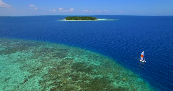 Aerial drone view of a man and woman sailing on a boat to a tropical island. alt
