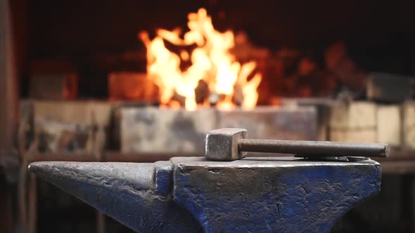 Hammer on Anvil in Forge on Furnace with Fire Background in Smithy Workshop.