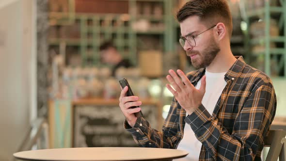 Upset Man Having Loss on Smartphone in Cafe  alt