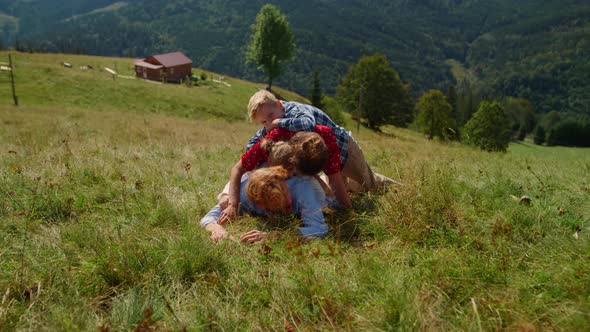 Happy Family Lying Piled Top Each Other on Green Hill alt