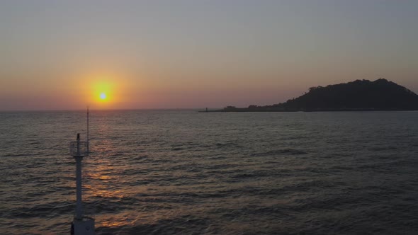 A romantic scenery where the setting sun illuminates the lighthouse and island alt