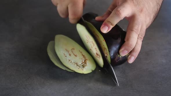 Man cutting eggplant with knife on the board