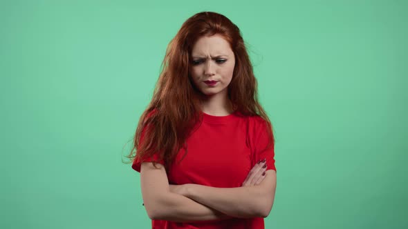 Offended Woman Keeping Arms Crossed Feeling Mad at Someone on Green Studio Background alt