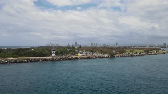 A aerial view crossing a boating channel with a large city skyline emerging from the ground alt