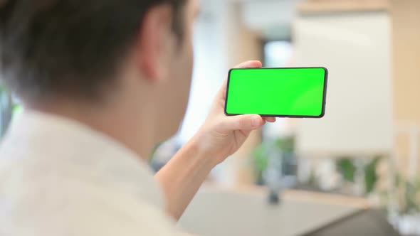 Young Man Looking at Smartphone with Green Chroma Screen alt