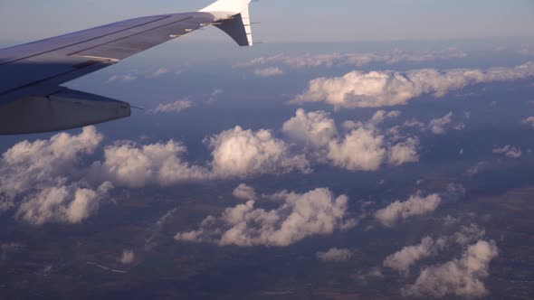 Airplane Wing Above White Cumulus Clouds in the Sky alt