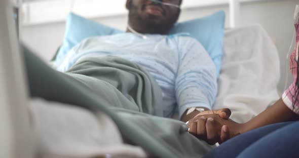 Cropped Shot of African Wife Visiting Husband in Hospital Holding Hands and Supporting alt