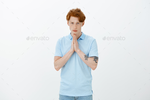 Please mom let me go to party. Cute european guy with ginger hair and tattoos, holding hands in pray