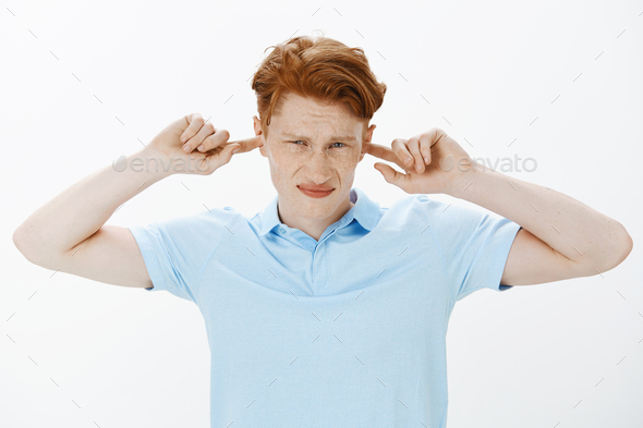 Turn this annoying sound off. Displeased annoyed attractive guy with ginger hair, growning and squin