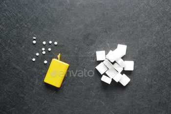 comparing artificial sweetener with white sugar on black background 